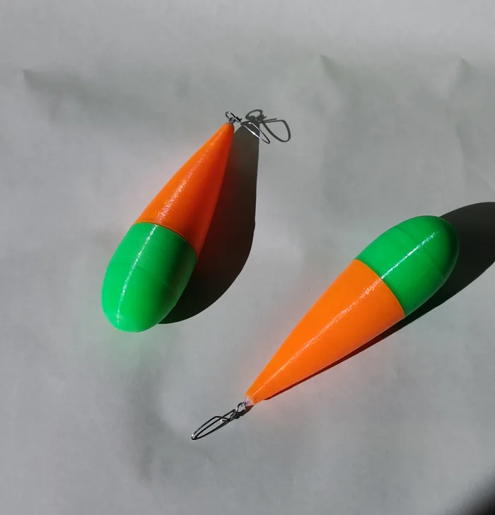 Dos boyas de pesca impresas en 3D, con el cuerpo en naranja y verde.