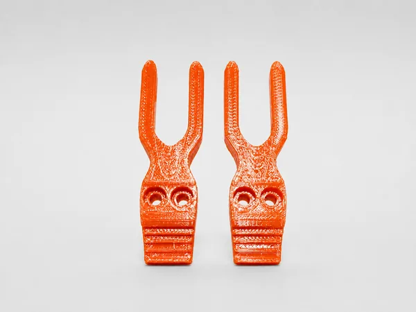 Par de horquillas impresas en 3D en naranja, con dos agujeros de fijación cada una.